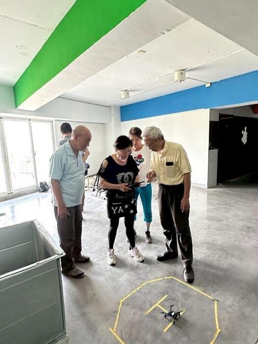 圖說：無人機訓練發展中心執行長張偉國副教授指導樂齡學員操控無人機。